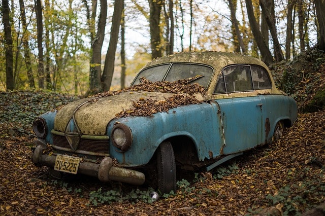 Stary, zniszczony samochód porzucony w lesie